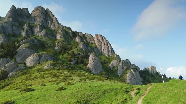 Hiker admiring dramatic rock formations of Tigaile Mari in Ciucas Mountains at summer sunset, scenic mountain landscape in Romania