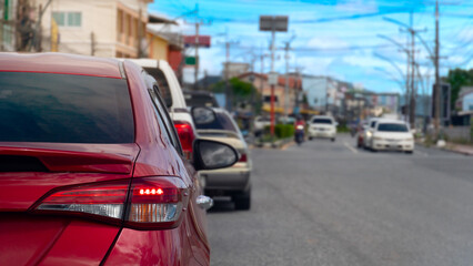 Rear side of red car with turn on brake light. Traffic jam in the city. Cars on the road queue in clear traffic conditions. Environment in the town at day of Thailand.