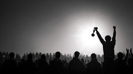 Silhouette of Victorious Person Holding Up a Medal in Front of Cheering Crowd at Sunset