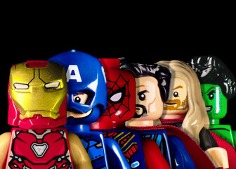 Naklejka premium LEGO Marvel Avengers stand behind each other. Marvel Iron Man, Captain America, Spider-Man, Doctor Strange, Thor, and Hulk faces on a black background