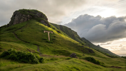 Majestic green hill with t shaped structure and dramatic clouds mountain grass