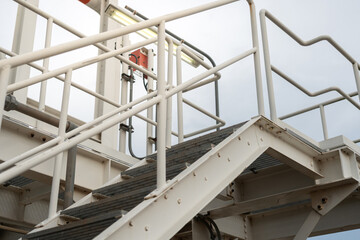 An overpass walkway across the production pipeline at the petrochemical and refinery plant. Industrial work place, close-up and selective focus.	