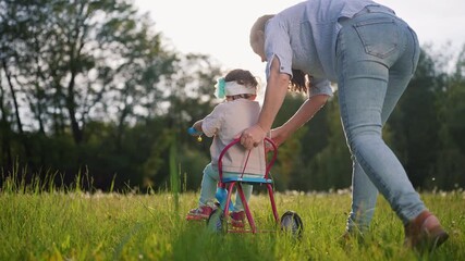 child rides a bike in the park.. happy family kid dream concept. Mother teaches the girl to ride a bike. mom and daughter toddler ride play in the park on summer a bicycle teaches on the grass