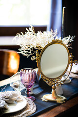 Retro vintage table. Arrangement on the table, antique mirror, plates, vintage mug. Ancient mirror on the table