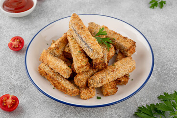 Baked crispy eggplant sticks served with tomatoes sauce on a plate on a gray concrete background. Vegetarian healthy dish. Selective focus