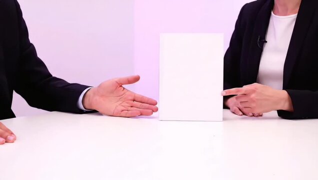Two business people in a corporate meeting presenting a new product idea using a blank white box mockup on a table
