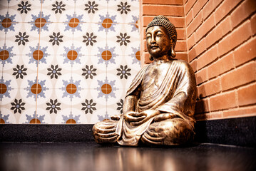 Golden Buddha Statue in Meditation Pose Against Decorative Wall
