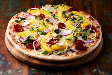 Pizza with chorizo ​​sausage, mozzarella cheese and yellow pepper. Rustic wooden background. Soft focus.	
