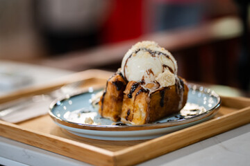 Honey Toast, a square toast baking with butter and topped with vanilla ice cream and chocolate sauce served with banana on blue plate.