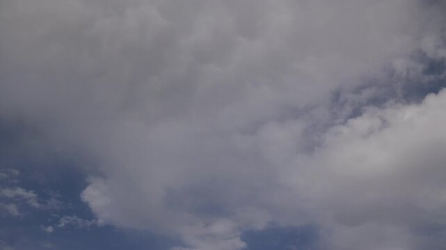 Low-angle time-lapse footage of the white clouds rolling in the blue sky on a sunny afternoon