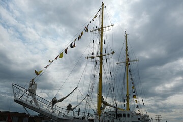 masts of a sailing ship with flags against a sky with clouds
