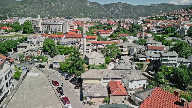 4k Drone video in tracking movement around Nezir Agina Mosque in Mostar, Bosnia and Herzegovina, with Hajji Kurt Mosque and the abandoned Mostar Marriott Hotel visible in the background during the day