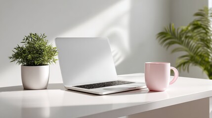 Fototapeta premium Bright Workspace Featuring Laptop, Plant, and Mug on White Desk for Creative Professionals
