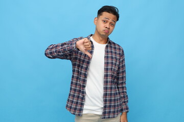 Sad, disappointed and upset young asian man wearing casual clothes with dislike gesture showing...