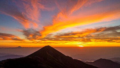 A fiery sunrise paints the sky above jagged mountain peaks and rolling hills, a vibrant landscape awakening