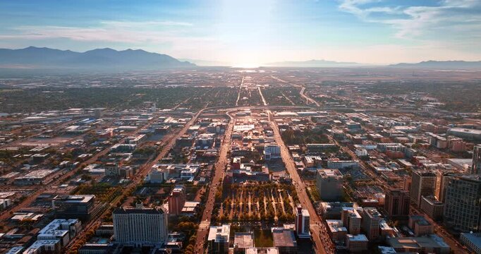 Straight parallel roads cross the urban landscape of the large city. Mountain silhouettes surround the territory of Salt Lake City, Utah, USA. Aerial view.