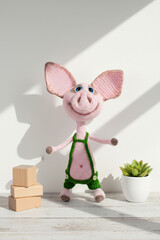Knitted toy pig in green shorts