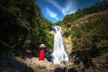 The Thai lady wearing red evening dressing with cream hat at the Sarika Waterfall at Nakhorn Nayork province. 
