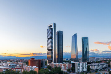 Cityscape of Madrid&rsquo;s financial district at dusk, featuring modern skyscrapers illuminated against the fading evening sky.