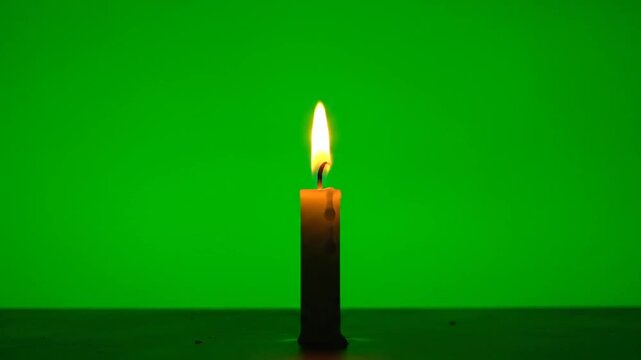 burning candle on green background