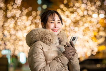 スマホを持った女性　クリスマスイルミネーション