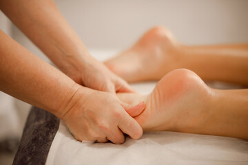 woman professional masseuse doing medical foot massage on massage table