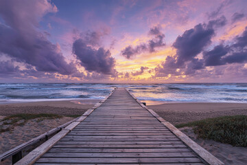 Fototapeta premium Colorful sunset over the ocean from a wooden pier with vibrant clouds illuminating the sky