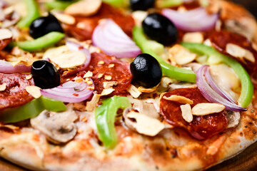 Pizza with chorizo ​​sausage, mozzarella cheese, green pepper and black olives. Rustic wooden background. Soft focus.	