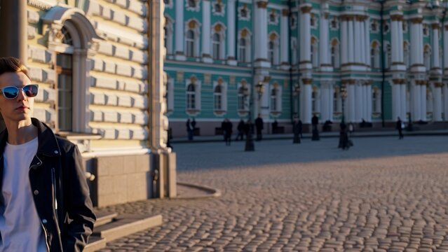 Man in sunglasses standing in front of building. Architecture of building with cobblestone street. Tourists in a jacket during a city sightseeing. A man wearing sunglasses is standing in lifestyle.