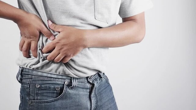 Close-up. A man's hand is holding his stomach and massaging it. The man in the shirt and shirt is experiencing abdominal pain on the right side. The sick man is suffering from liver disease, gastritis