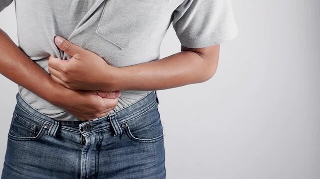 Man having pains in stomach. Young man suffering from a belly ache. Cropped shot of a sick man with an ulcer, IBS, colitis, or dyspepsia holding hands on his abdomen. Health problems concept
