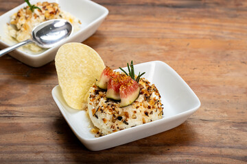 Cheese terrine Gourmet appetizer with figs and chips on a rustic wooden table.