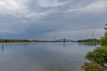 Tranquil waterfront scene at Little Current, Manitoulin Island, featuring the historic swing bridge against a serene sky and calm waters.