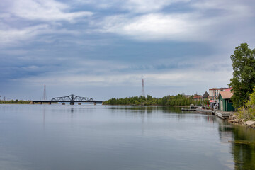 Tranquil waterfront scene at Little Current, Manitoulin Island, featuring the historic swing bridge against a serene sky and calm waters.
