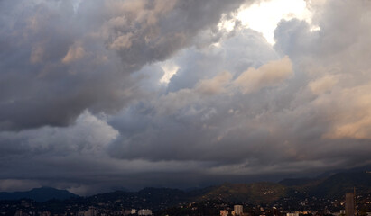 Fototapeta premium Bid fluffy clouds over the mountains on stormy weather, village, houses in the mountains. 