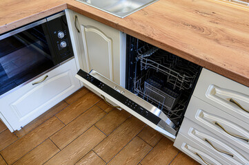 kitchen corner featuring an open dishwasher, adjacent to an oven, with wooden countertops and tiled flooring
