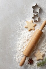 Wooden rolling pin rests on flour-dusted surface with star-shaped cookie cutters and baked cookies, creating a festive atmosphere for holiday baking and culinary creativity