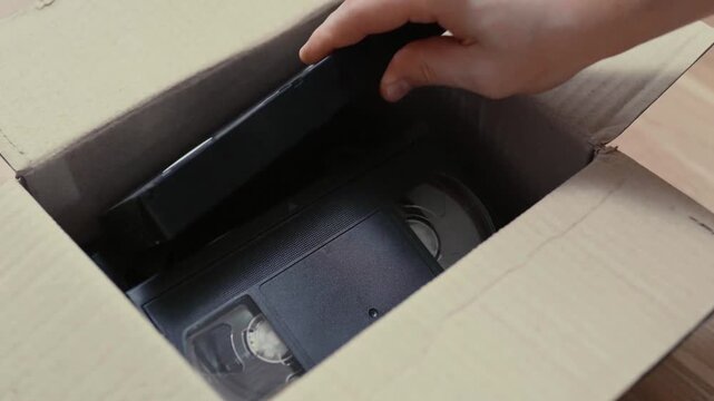 An old box with retro VHS tapes on a floor.