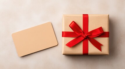 Gift box wrapped in brown paper with a vibrant red ribbon sits on a soft textured surface beside a blank tag for personalized messages and celebrations