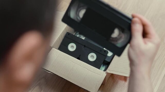 An old box with retro video cassettes on a floor.