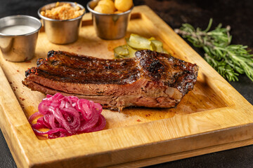 Smoked beef brisket with side dishes on wooden board