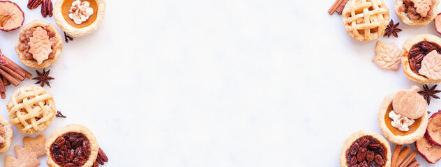 Fall pie theme dessert double border. Overhead view against a white marble banner background. Pumpkin, apple and pecan mini pies.