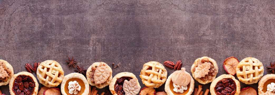 Autumn pie theme dessert bottom border. Top view against a dark stone banner background. Pumpkin, apple and pecan mini pies. - Powered by Adobe