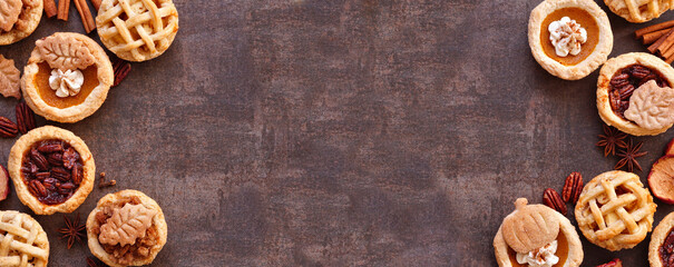 Fall pie theme dessert double border. Top down view against a dark stone banner background. Pumpkin, apple and pecan mini pies.