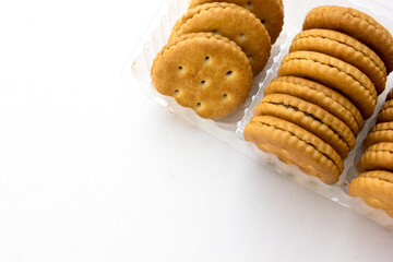 Several stacks of golden crackers in the transparent container, isolated on white background, showcasing their round shape and crispy texture. 