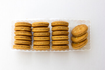 Several stacks of golden crackers in the transparent container, isolated on white background, showcasing their round shape and crispy texture. 
