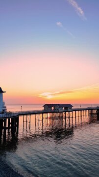 Aerial drone footage of sunrise above Penarth pier. Vertical tracking shot from left to right.