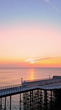 Aerial drone footage of sunrise above Penarth pier. Vertical pull out shot.