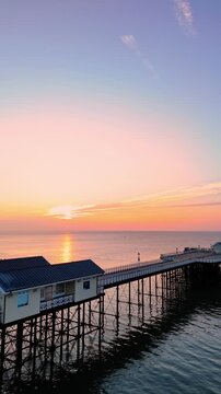 Aerial drone footage of sunrise above Penarth pier. Vertical panning shot from left to right.