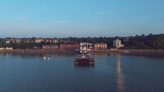 Aerial drone footage of Penarth seafront at sunrise overlooking the pier and residential areas. High altitude revealing pull out shot.